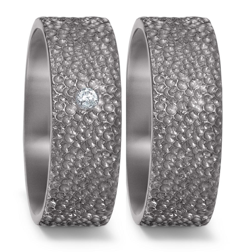 Partnerring Eleganter Damen-Partnerring aus robustem Tantal mit einer markanten, strukturierten Oberfläche. Der Ring ist mit einem funkelnden Diamanten besetzt und vereint modernes Design mit zeitloser Eleganz – perfekt für besondere Momente und bleibende Verbindungen. 52561/001/003/X000